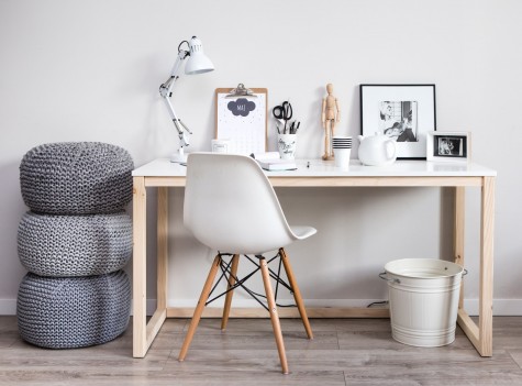 Biurko z prostokątnym blatem na drewnianej podstawie oraz białe krzesło w stylu skandynawskim