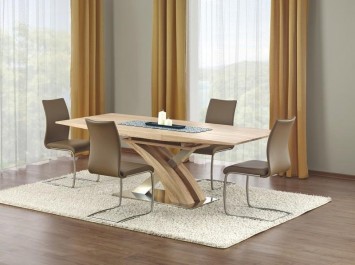 Rozkładany stół w imitacji drewna na ozdobnej nodze w towarzystwie nowoczesnych krzeseł na płozach