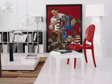 Czerwone krzesło o połyskującej powierzchni bez podłokietników i biały stolik pomocniczy w awangardowym wnętrzu salonowym
