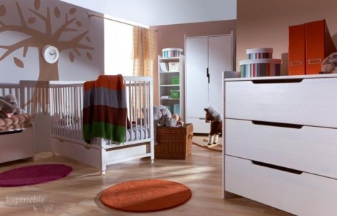 Drewniane łóżeczko na kółkach w dużym pokoju dziecięcym z drewnopodobną podłogą