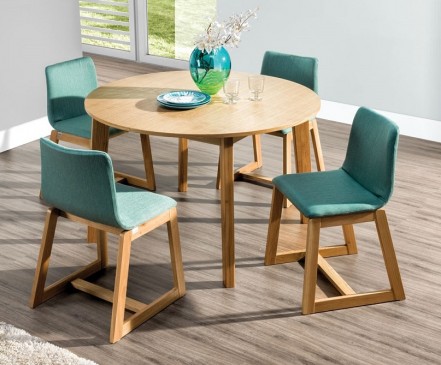 Rozkładany okrągły stół z fornirowanym blatem i zielone tapicerowane krzesła na drewnianych płozach