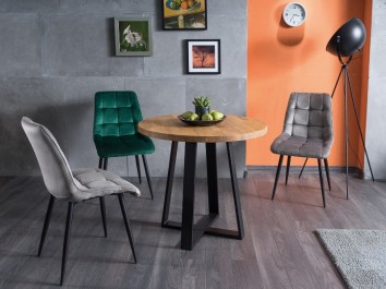 Okrągły stół w stylu industrialnym z tapicerowanymi krzesłami w jadalni połączonej z salonem