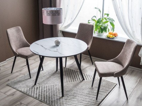 Okrągły stół na metalowych nogach z tapicerowanymi krzesłami na popielatym dywanie